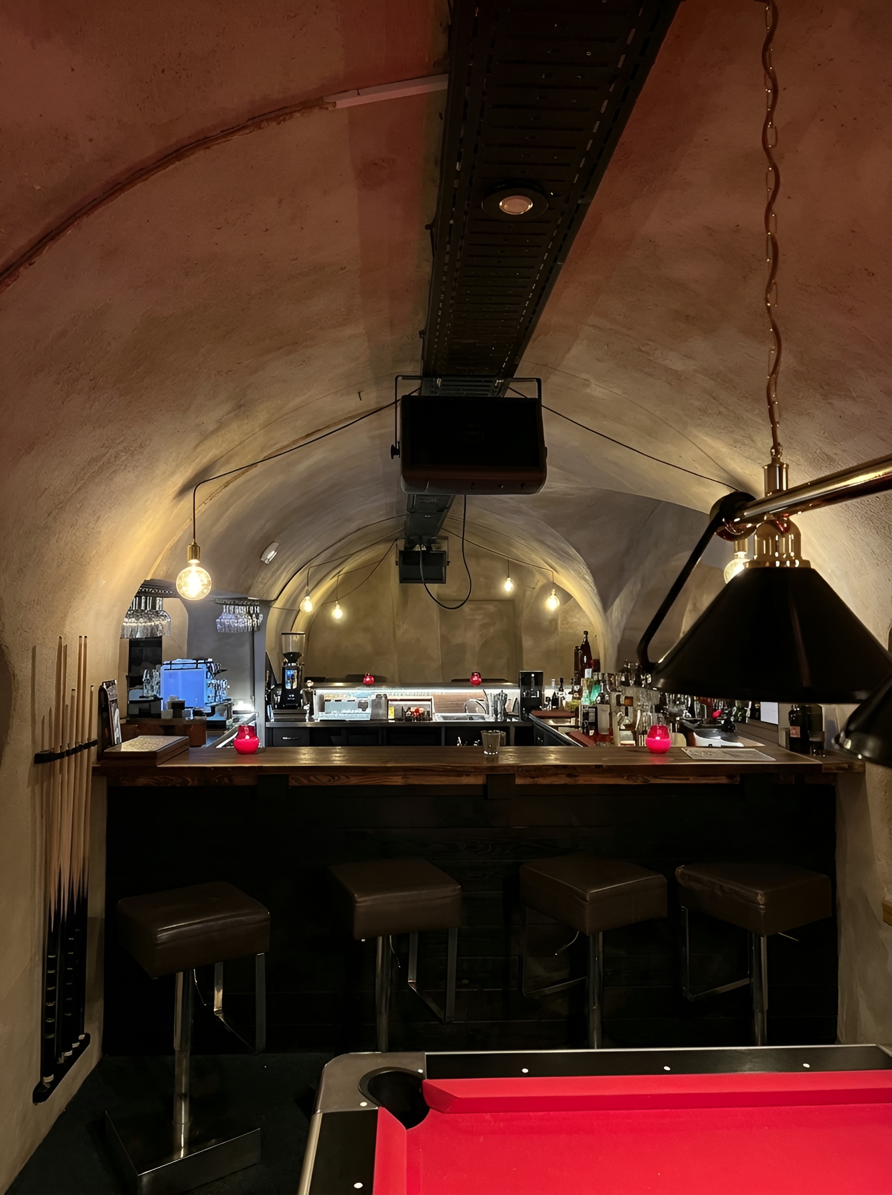 Blick von vorne auf die Bar unter dem Gewölbe, mit Hockern und Billardtisch